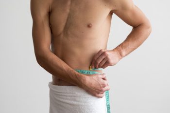 front-view-shirtless-man-measuring-his-waste-with-tape